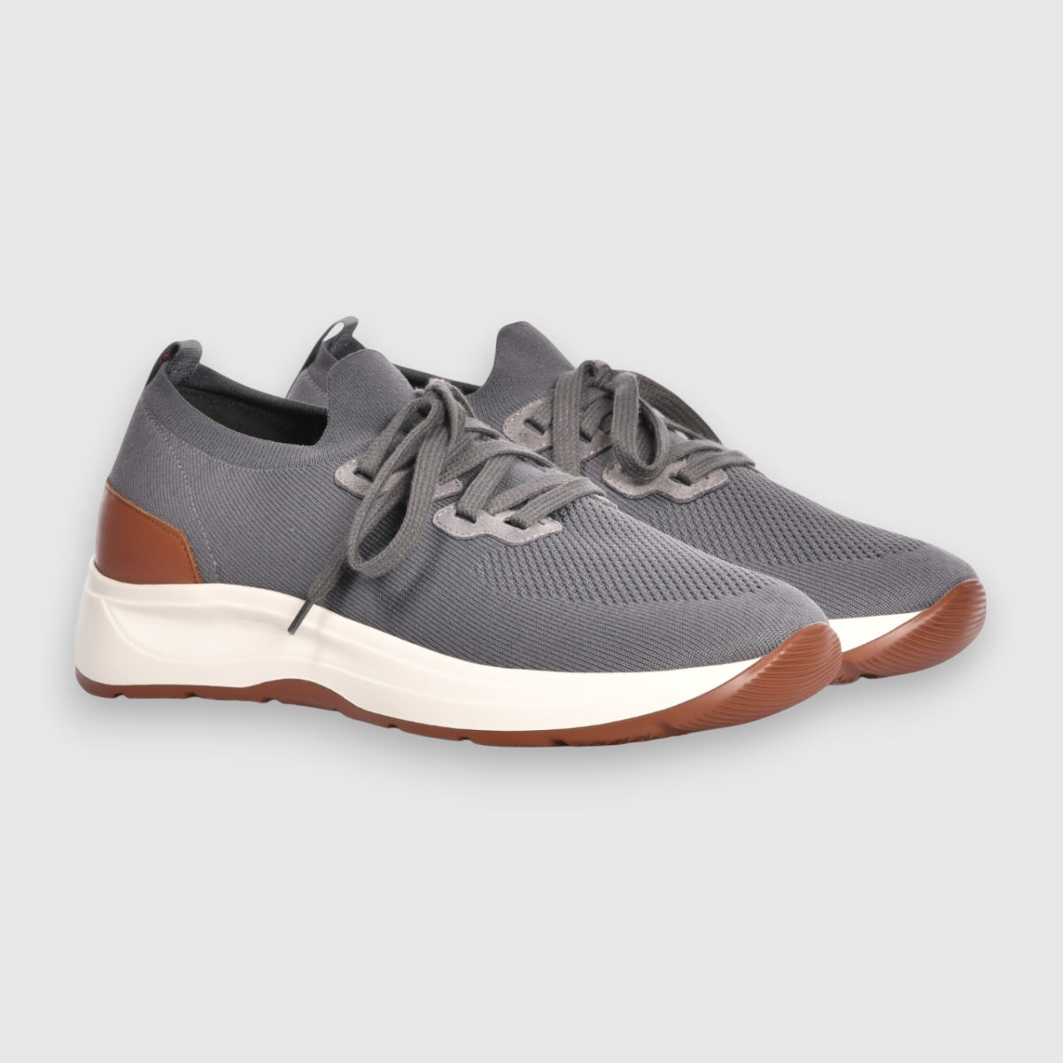 The Gran Sasso Grey Knitted Sneaker features thick white soles, brown accents on the heel and toe, and matching gray laces, displayed side by side on a light gray background for a comfortable footwear option. , available at Richard Gelding Mayfair