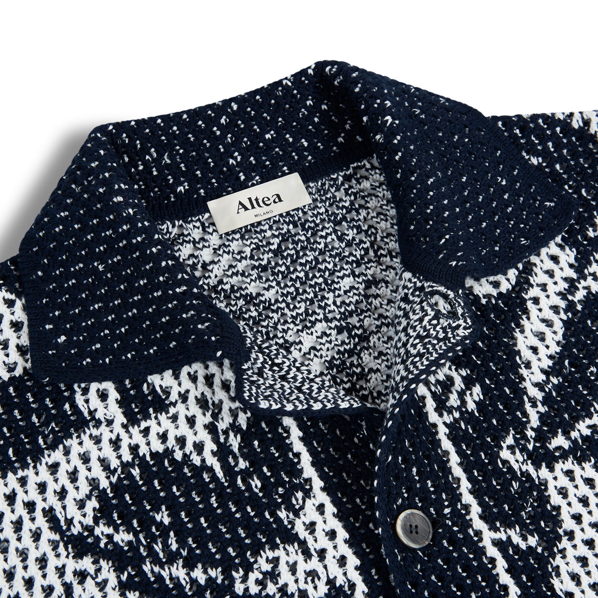 Close-up of Altea's Navy Cream Cotton Flower Open Weave shirt with a collar. A dark button on the placket and the label inside highlight its breathable cotton fabric and textured knit design. , available at Richard Gelding Mayfair