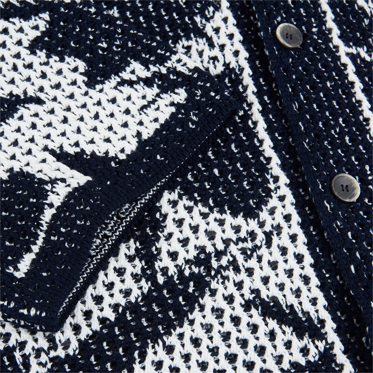 Close-up of the Altea Navy Cream Cotton Flower Open Weave cardigan, featuring a breathable mesh-like cotton knit, geometric pattern, front pocket, and black buttons. The partially open pocket reveals the airy textured design. , available at Richard Gelding Mayfair