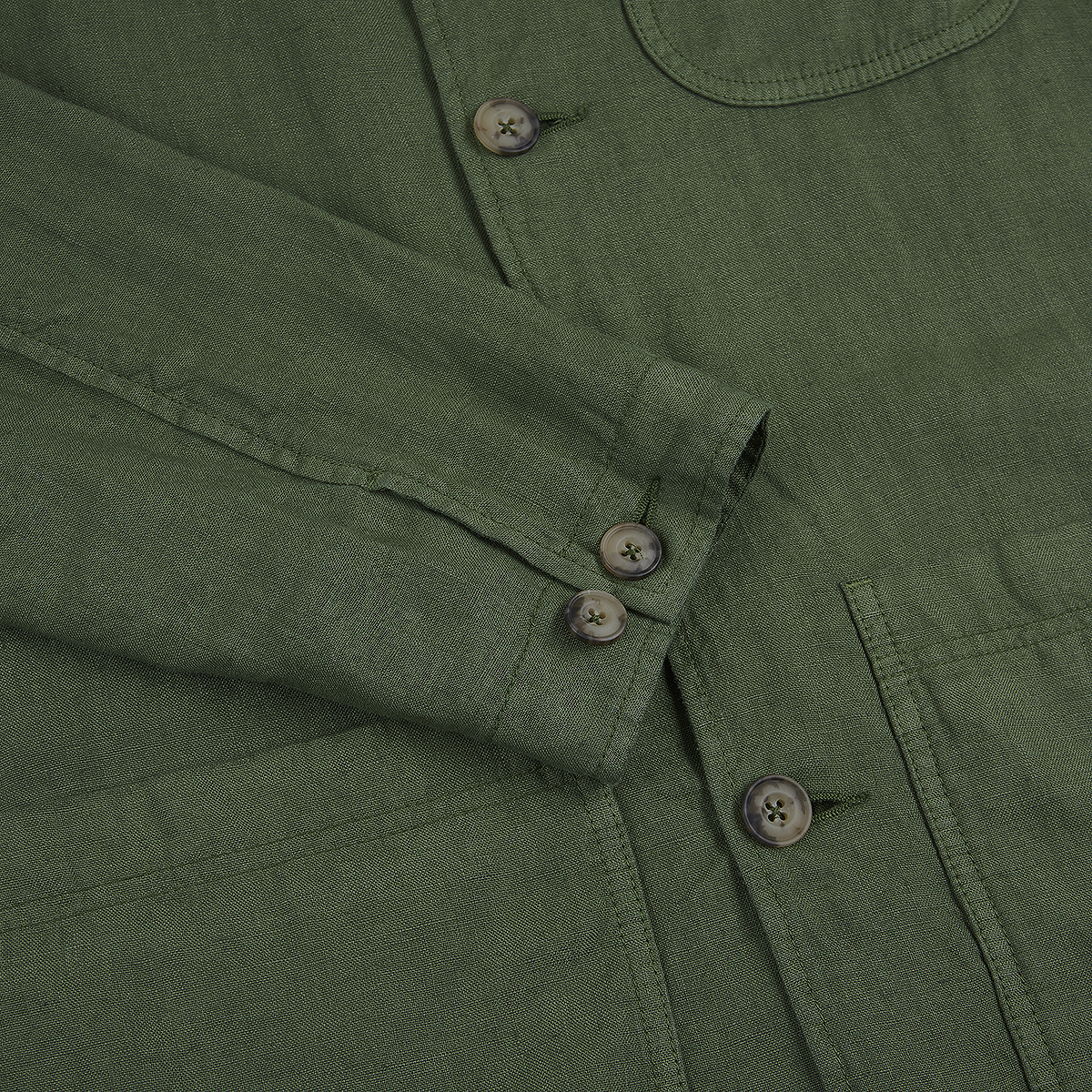 Close-up of the Altea Army Green Linen Chore Jacket, highlighting the sleeve crossed over the front, visible stitching, three brown cuff buttons, and a large brown button by a patch pocket. , available at Richard Gelding Mayfair