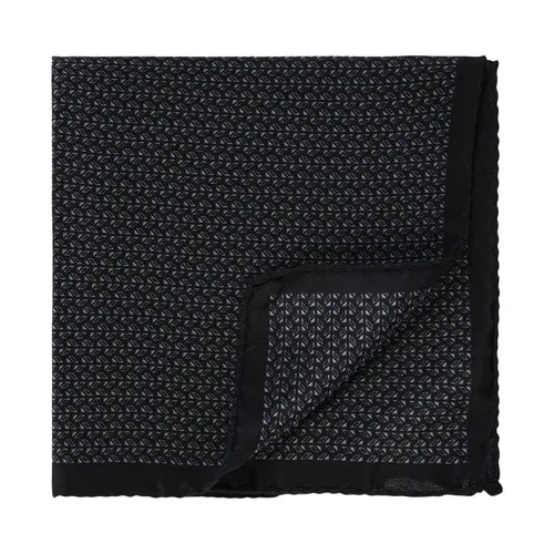 A neatly folded Amanda Christensen silk pocket square with a small, repeating light gray micro pattern on black. One corner is turned up to reveal the reverse side, displaying the same design. The edges feature a plain black trim, set against a plain white background. , available at Richard Gelding Mayfair