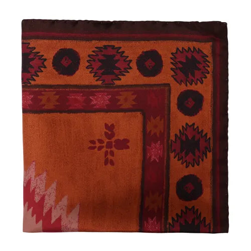 A silk pocket square by Amanda Christensen, featuring an Inca-inspired pattern in orange and red tones, with geometric designs, a border of dark red circular motifs, a central small element, and angular accents in one corner. The edges are neatly folded, highlighting the smooth and soft texture of the printed silk. , available at Richard Gelding Mayfair