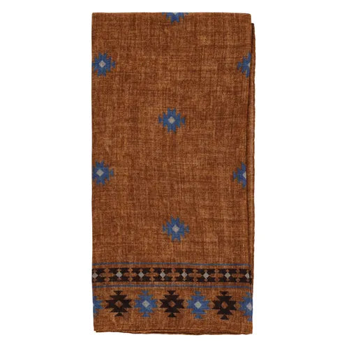 A folded brown wool bandana from Amanda Christensen features an Inca-inspired blue geometric print and a striking black and blue patterned border along one edge. The woven texture and elegant, simple design make it versatile as a scarf, shawl, or decorative accessory. , available at Richard Gelding Mayfair