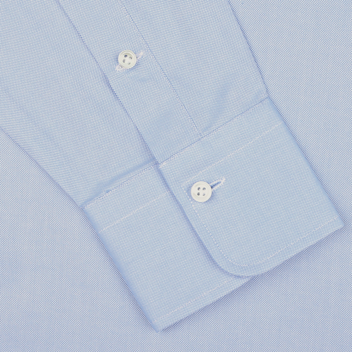Close-up view of the cuff of an Alessandro Gherardi Light Blue Cotton Oxford Single Cuff Shirt, featuring two white buttons and crafted from pure cotton oxford, on a plain background.