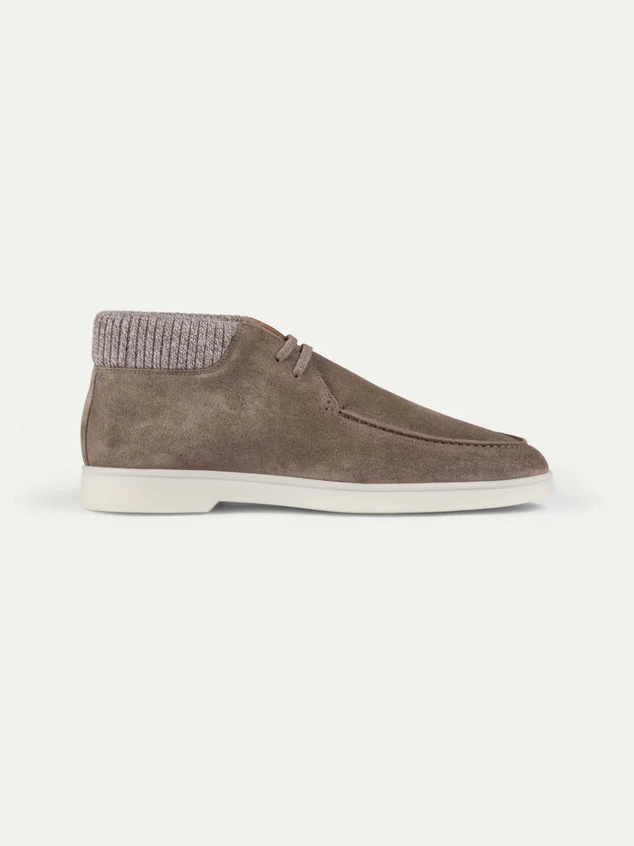 Introducing the Ash Grey Suede Desert Boots with Cashwool Trim by Aurélien—an ankle-high shoe crafted from taupe suede, featuring moccasin-style stitching, a ribbed knit collar, white sole, and laces. Inspired by Italian craftsmanship and reminiscent of classic Aurélien desert boots, these minimalist shoes are photographed from the side on a white background for a clean, casual look. , available at Richard Gelding Mayfair