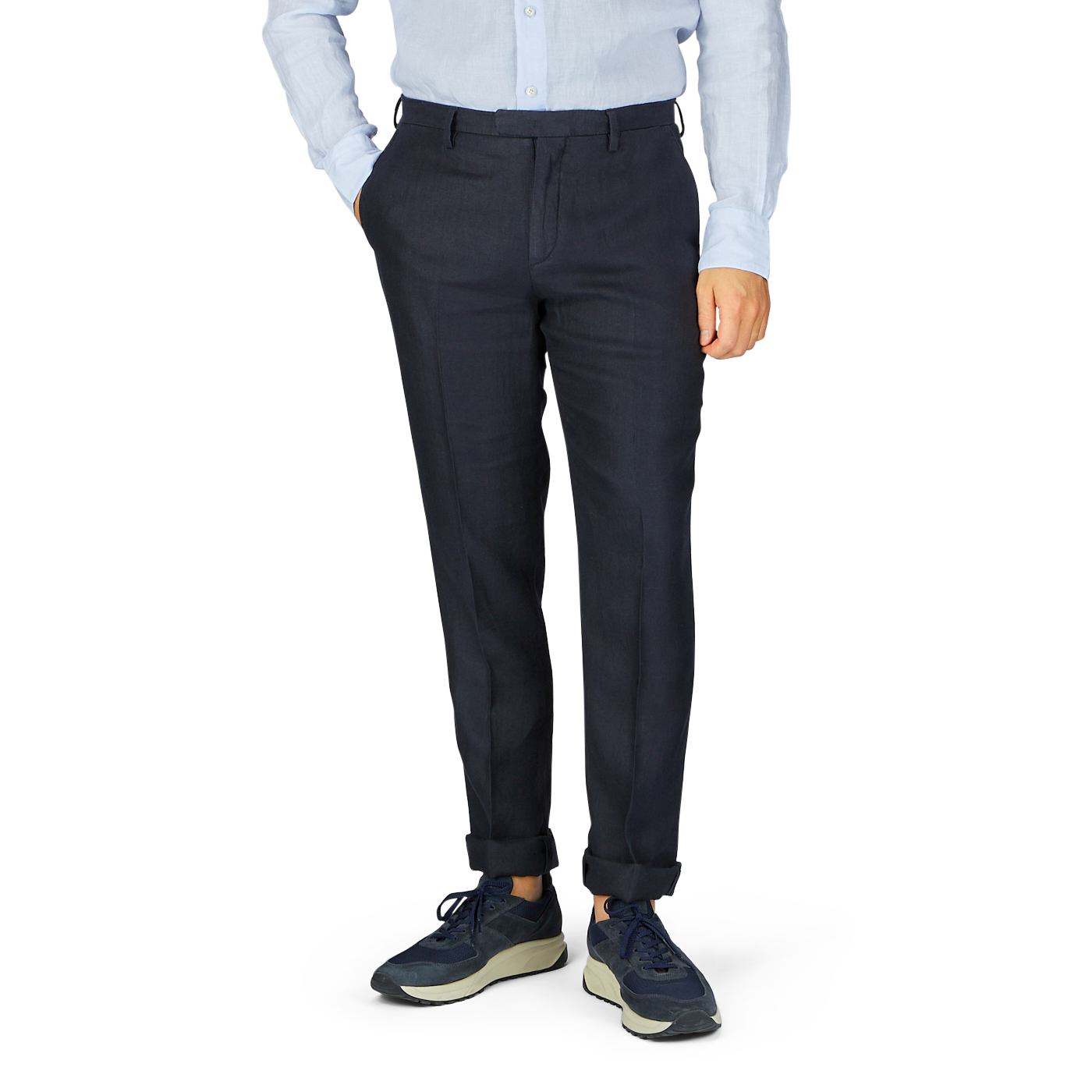 Man wearing a light blue, pure linen shirt, Boglioli navy blue washed Irish linen trousers, and sneakers, standing against a neutral background.