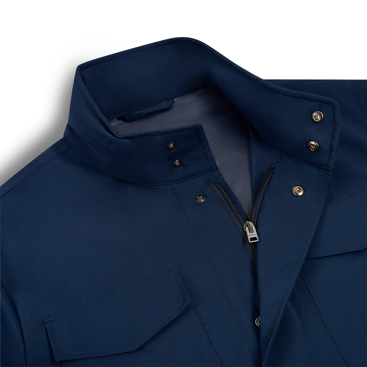 A close-up of the Manto Navy Japanese Nylon Andromeda Packable Field Jacket highlights Japanese precision in its standing collar with snap buttons, silver zipper, and flap chest pocket. The smooth, lightweight fabric stands out against a light background. , available at Richard Gelding Mayfair