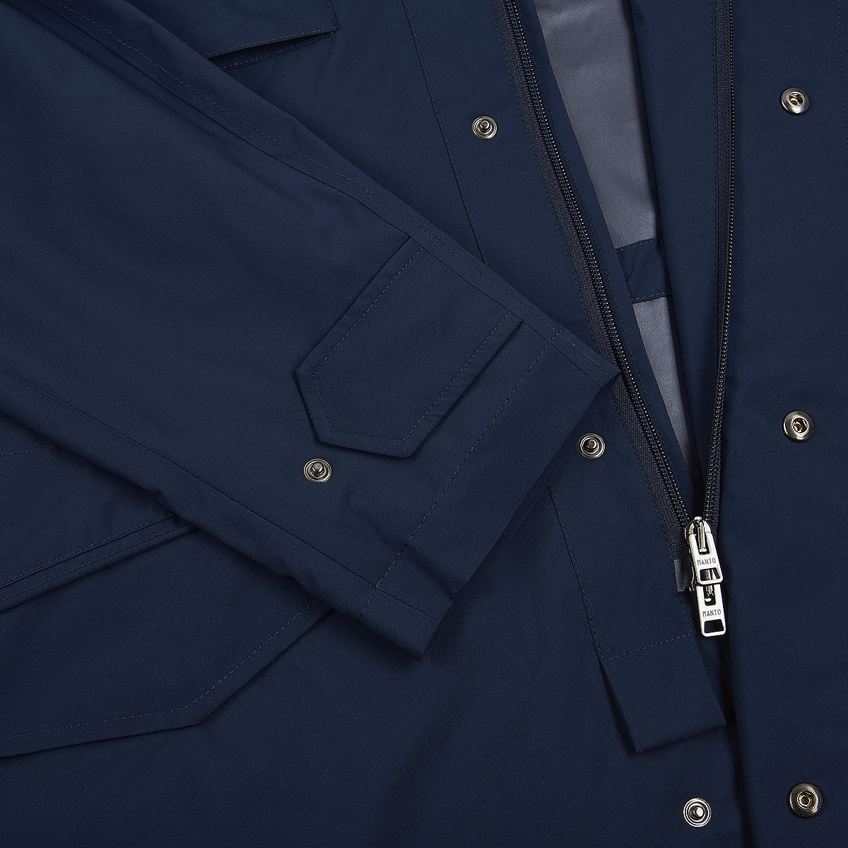 Close-up of the Manto Navy Japanese Nylon Andromeda Packable Field Jacket, showing a sleeve with a rectangular flap, silver snap buttons, a partially unzipped zipper, and tailored stitching that highlights Japanese craftsmanship and detailed inner lining. , available at Richard Gelding Mayfair