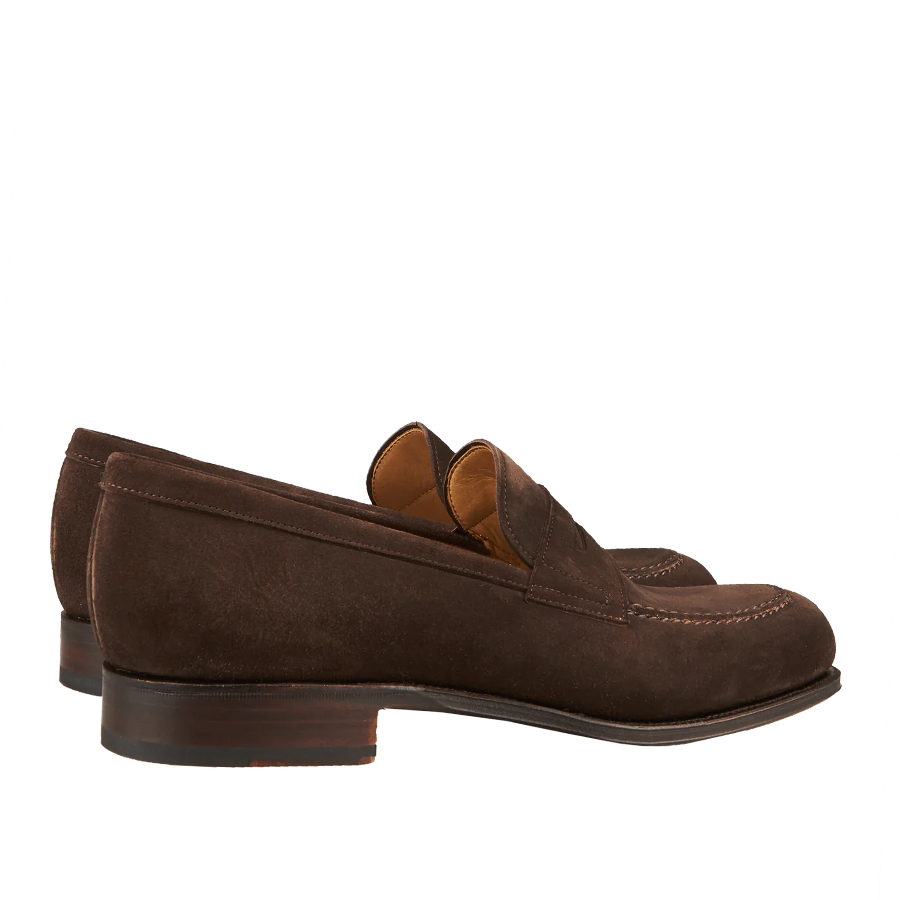 A pair of Carmina brown suede forest penny loafers on a striped background.