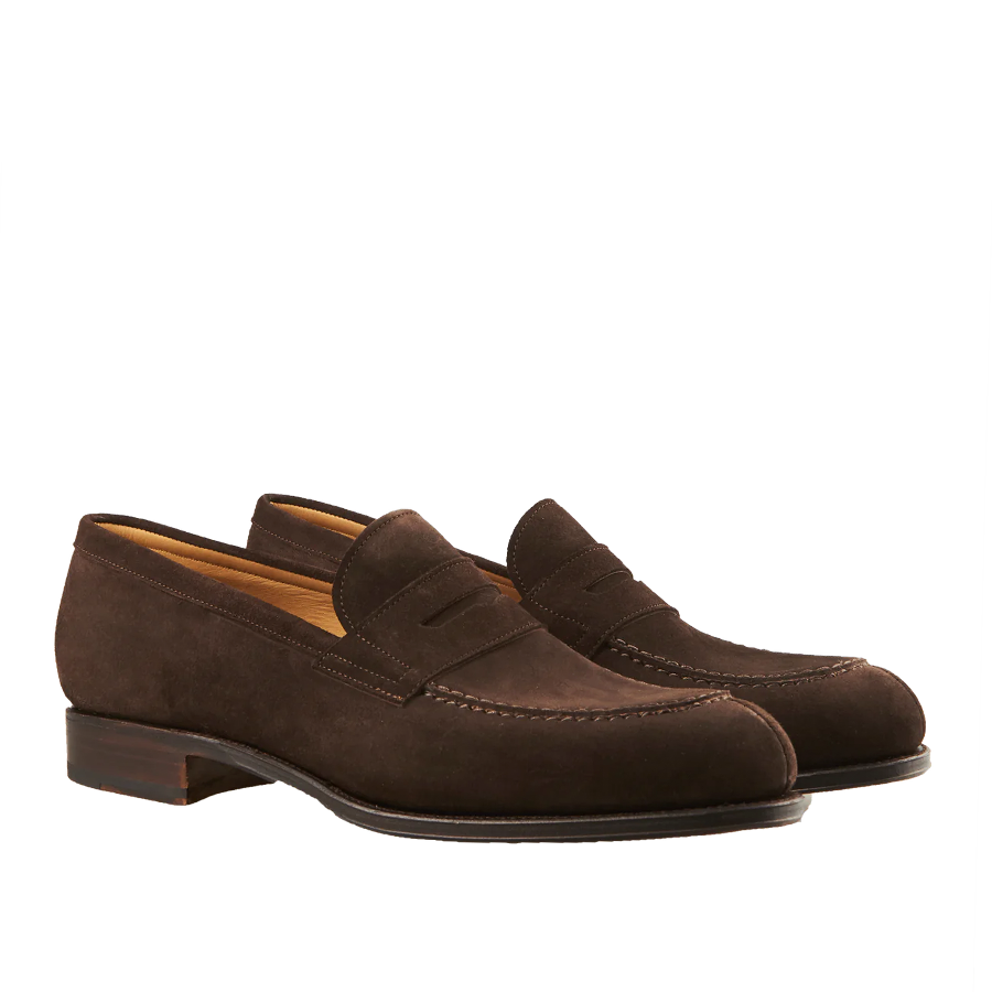 A pair of Carmina Brown Suede Forest Penny Loafers crafted by expert craftsmen, set against a striped background.