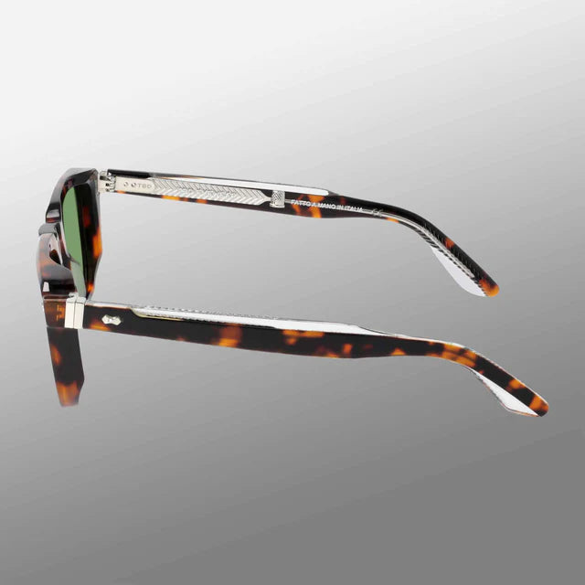 Side view of TBD Eyewear Dart Brown Havana | Green sunglasses with thick, tapered recyclable acetate frames, silver accents by the hinges, and dark-tinted lenses on a gray gradient background. , available at Richard Gelding Mayfair