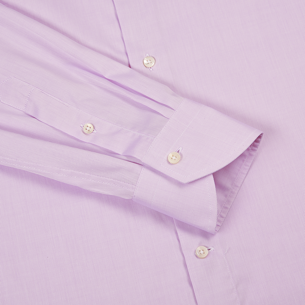 A close-up of the Canali Pink Textured Cotton Regular Fit Shirt shows the sleeve, cuff, and part of the body with white buttons. The finely textured fabric and unbuttoned cuff are neatly folded against the shirt. , available at Richard Gelding Mayfair