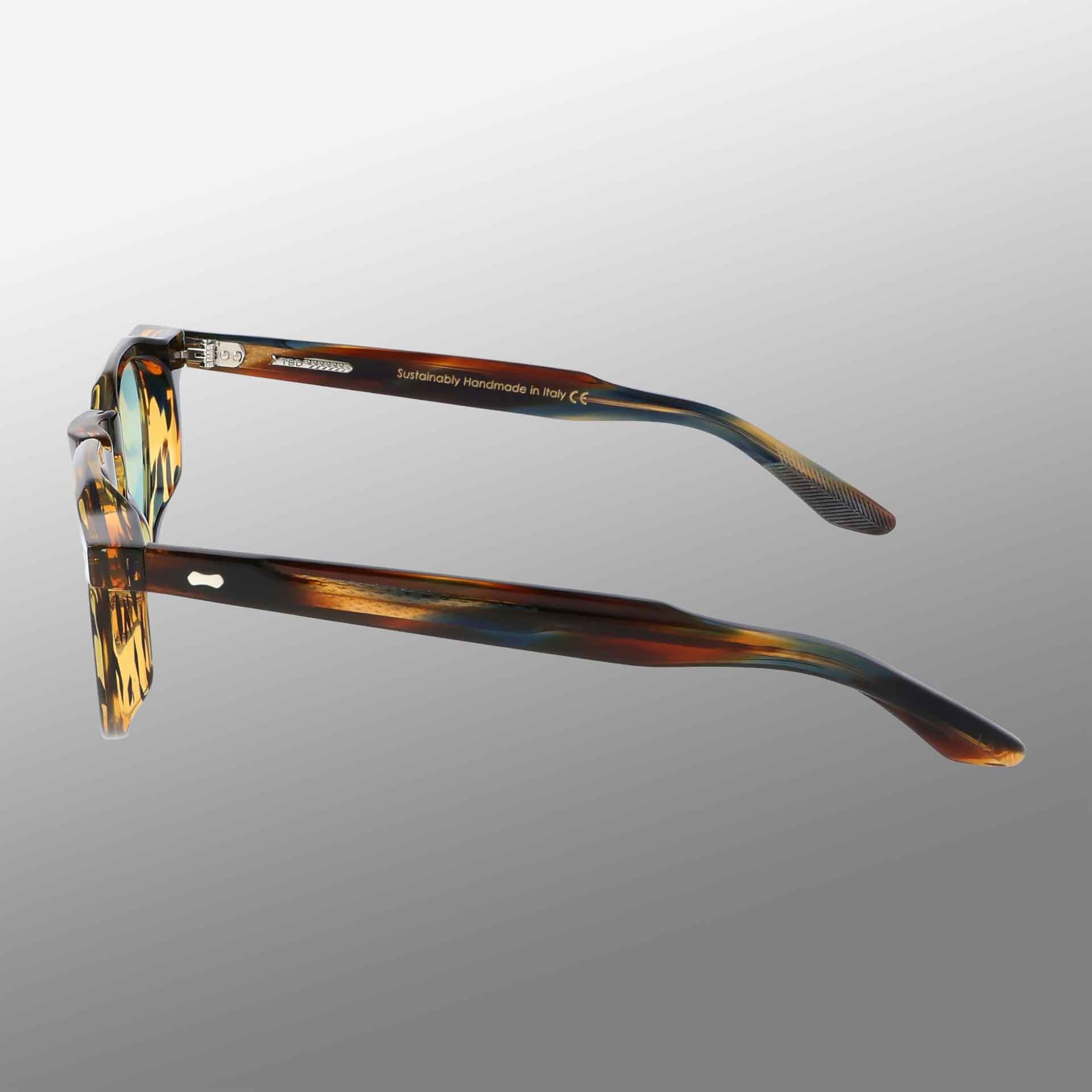 A pair of TBD Eyewear Hem River | Light Green eyeglasses is shown from a side angle on a gray gradient background, with “Sustainably Handcrafted in Italy” in white on the inside of the left arm. , available at Richard Gelding Mayfair