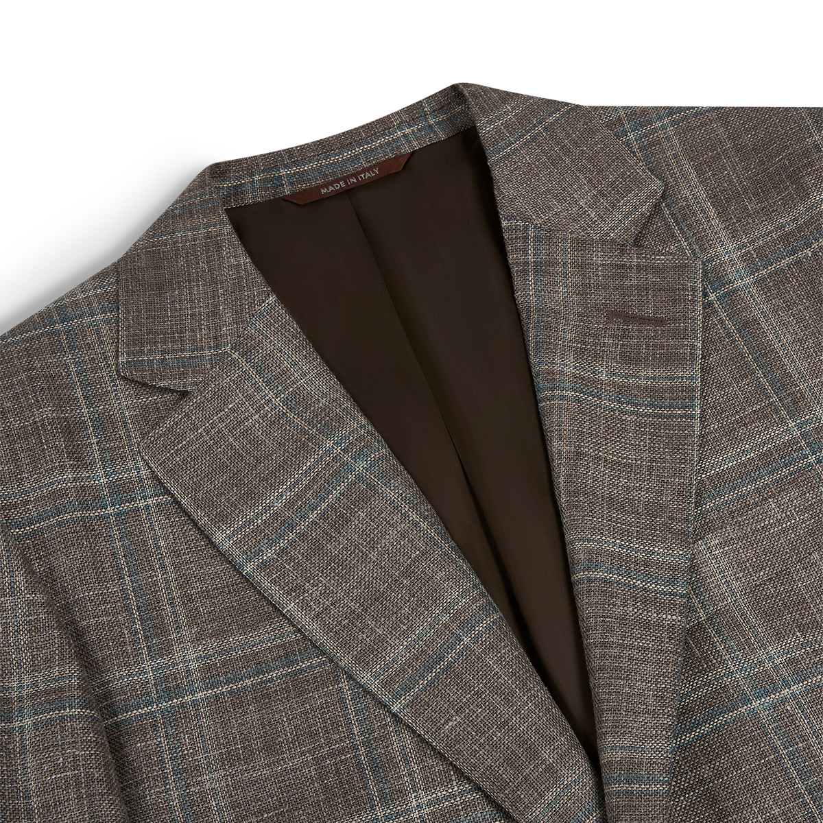 Close-up of the Canali Stone Teal Wool/Silk/Linen Windowpane Check Blazer, featuring light blue and beige stripes, notch lapels, brown lining, and a "Made in Italy" collar tag. The textured fabric is shown on a white background. , available at Richard Gelding Mayfair