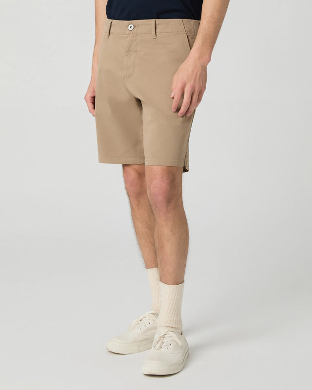 A model wears Paige Beige Farro Phillips Cotton Stretch Shorts, standing against a light gray background. The focus is on the shorts and legs; the shirt, socks, and shoes are visible, but the face and upper body are out of frame. , available at Richard Gelding Mayfair