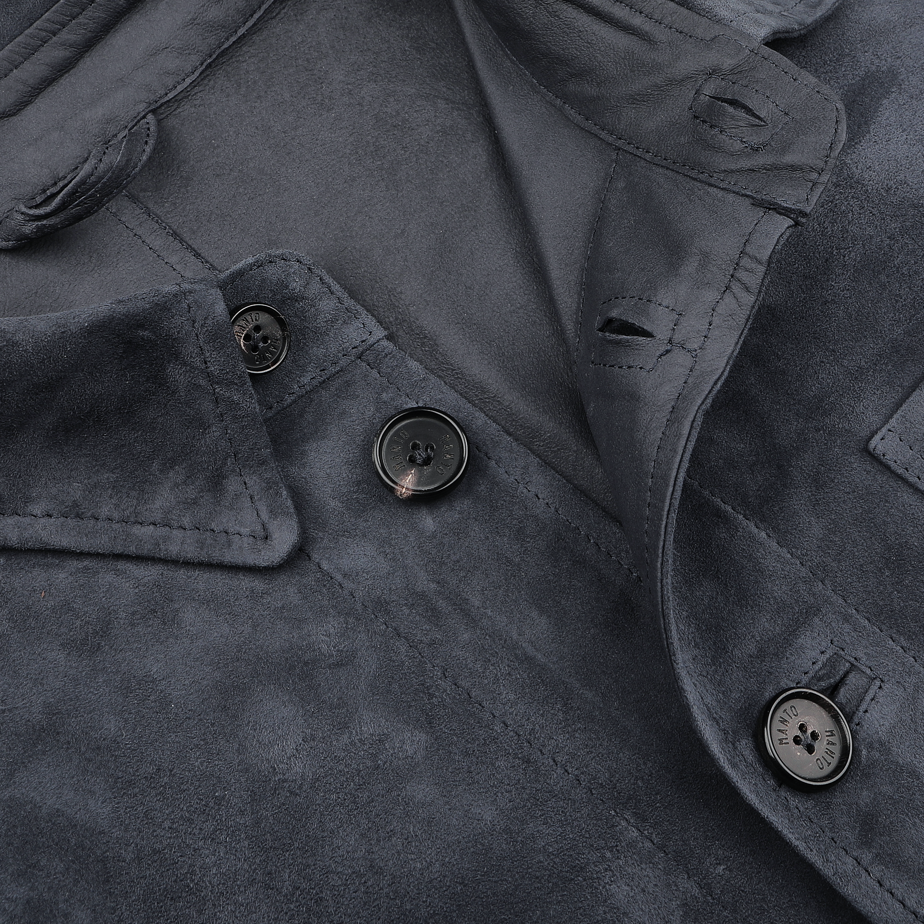 Close-up of a denim blue suede jacket by Manto featuring three black buttons and folded collar details, showcasing its slim fit design.