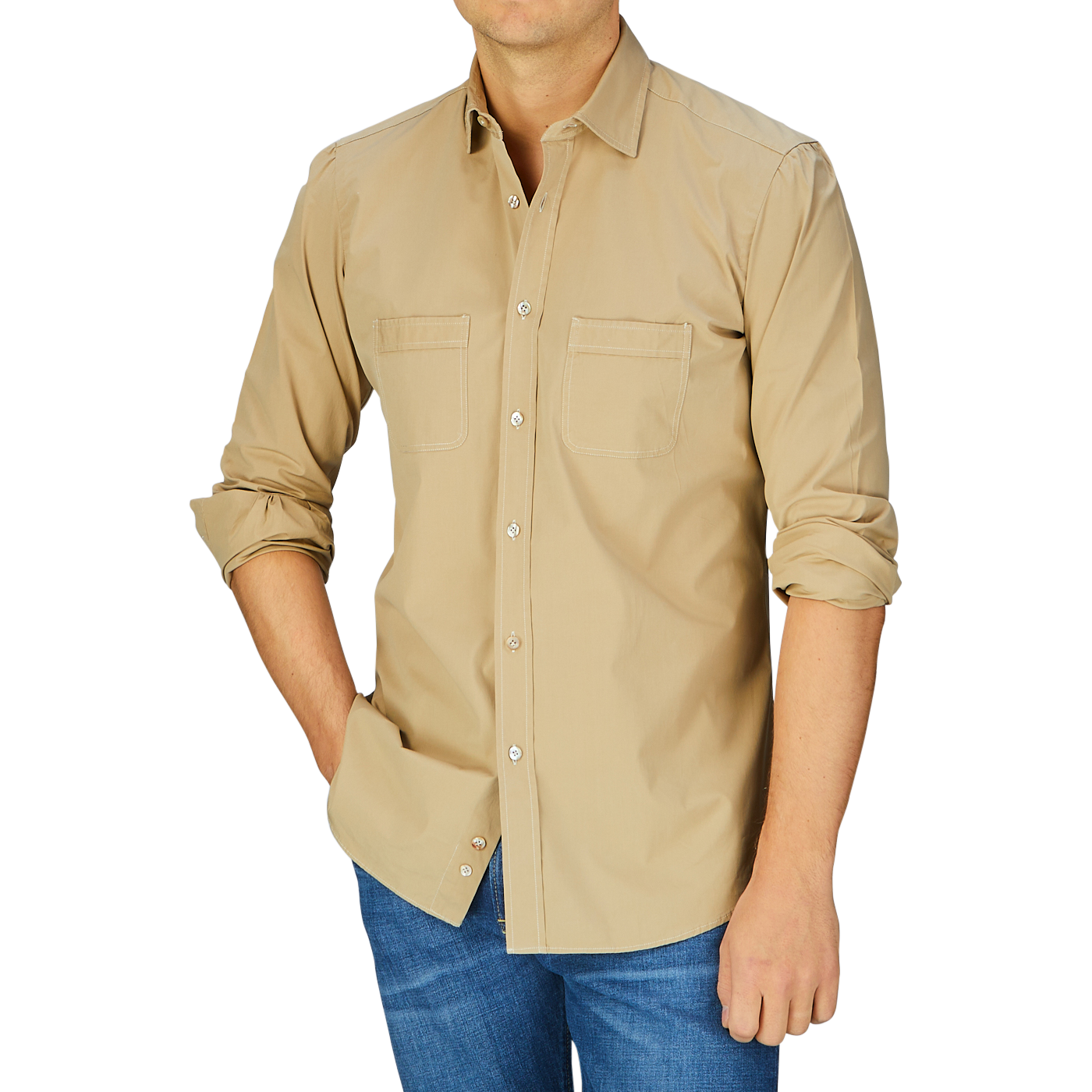 A man wearing a Khaki Beige Cotton Gabardine Regular Fit Shirt by Italian shirtmaker Mazzarelli and stone-washed blue jeans against a blue background.