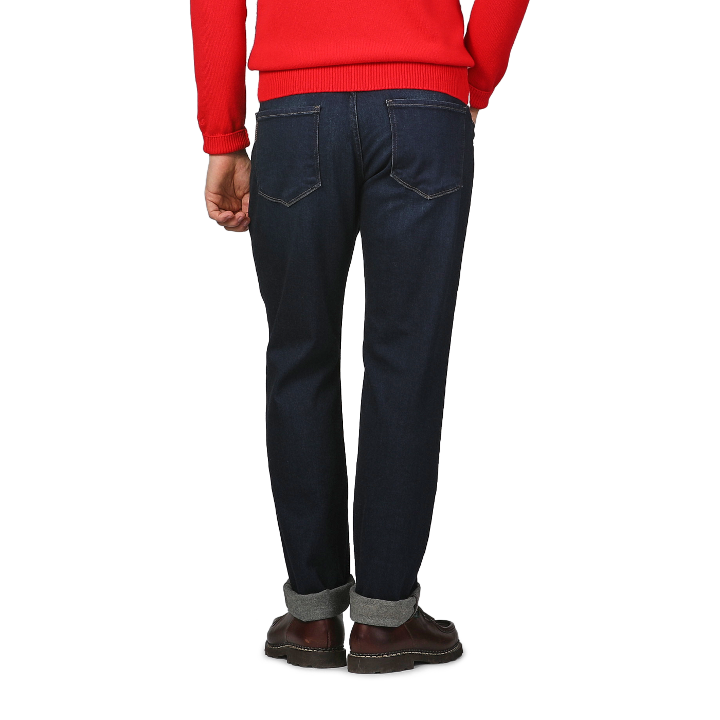 A person in a red sweater and Paige's Blue Faded Cotton Cramer Normandie Jeans stands with their back facing the camera, wearing brown shoes.