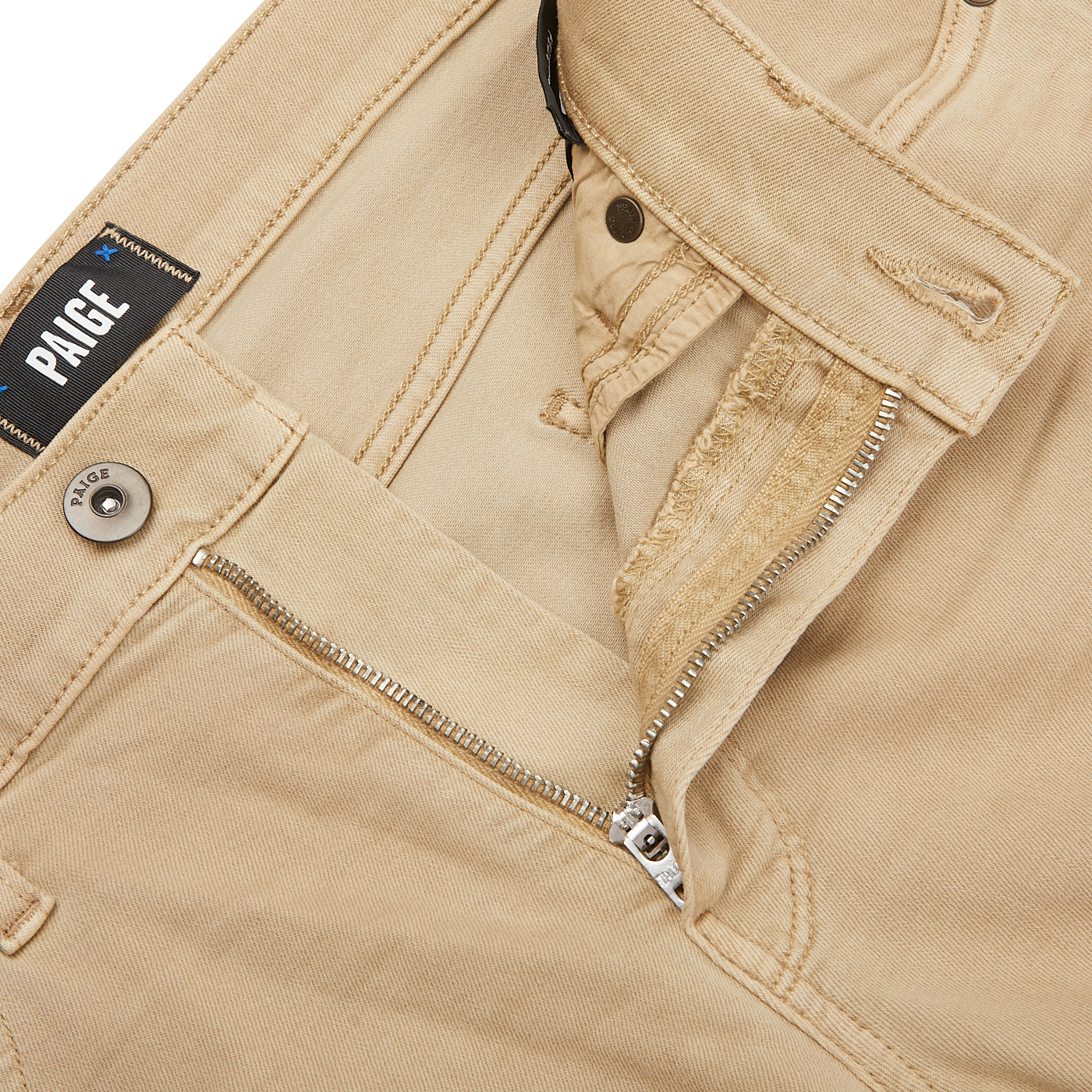 Close-up of Caramel Beige Cotton Transcend Federal Slim Jeans with a partially open zipper and button. The brand label "Paige" is visible above the pocket, showcasing the comfortable fit and luxurious Transcend fabric.