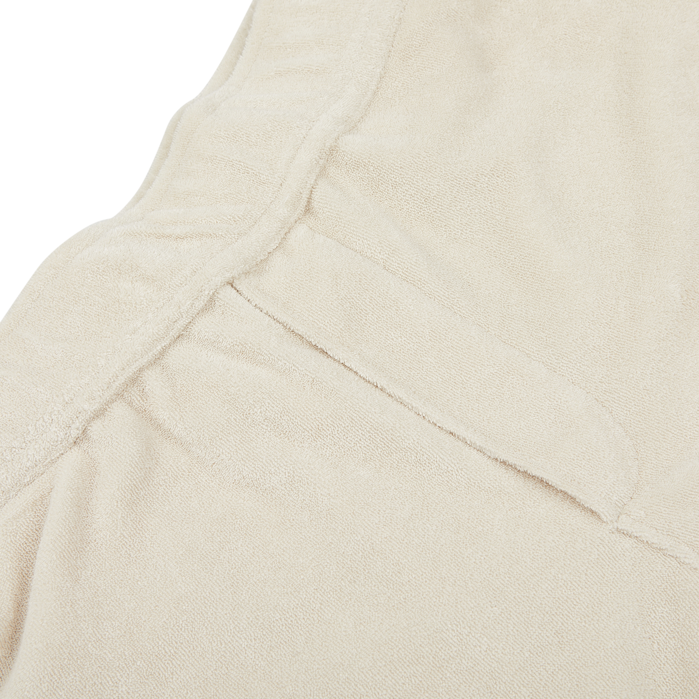 Close-up view of a beige fabric with a seam and an overlapping flap, displaying a soft texture, perfect for summer shorts crafted from a towelling cotton blend. The Cream Beige Cotton Towelling Shorts by Paige exemplify this ideal material.