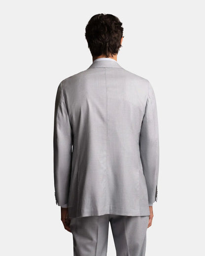 A person with short dark hair faces away, showcasing the relaxed fit of the Cavour Pale Blue Wool/Silk Puppytooth Suit against a plain white background, highlighting the back view of this refined two-piece. , available at Richard Gelding Mayfair