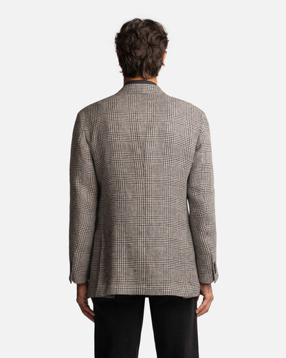 A person with short brown hair is seen from behind, wearing the Cavour Black/Grey Linen Glencheck Blazer paired with black pants, set against a plain white background. , available at Richard Gelding Mayfair