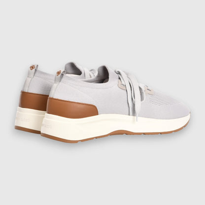 The Gran Sasso Light Grey Knitted Sneakers feature white laces, chunky white soles, and brown accents on the heel and outsole. These modern, sporty low-tops are set against a plain gray background. , available at Richard Gelding Mayfair