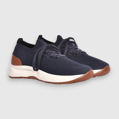 Gran Sasso Navy Blue Knitted Sneakers feature breathable knit fabric, white soles, brown accents on the heel and sole edge, and navy blue laces. Displayed against a plain light gray background. , available at Richard Gelding Mayfair