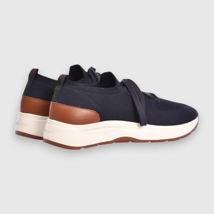 Gran Sasso Navy Blue Knitted Sneakers feature brown leather heel accents, thick white midsoles, brown rubber outsoles, navy laces, and a back pull tab, all set against a plain light gray background. , available at Richard Gelding Mayfair