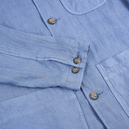 Close-up of the Altea Sugar Packet Blue Linen Chore Jacket, featuring a long sleeve with two brown cuff buttons, buttonholes, and a chest pocket. The soft, textured linen recalls relaxed Italian style. , available at Richard Gelding Mayfair