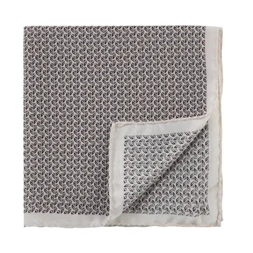 Amanda Christensen silk pocket square featuring a repeating black and white micro leaf pattern. The pocket square has a thin white border, and one corner is folded to reveal the same pattern on the reverse side. The edges are finished with a subtle fringe. , available at Richard Gelding Mayfair