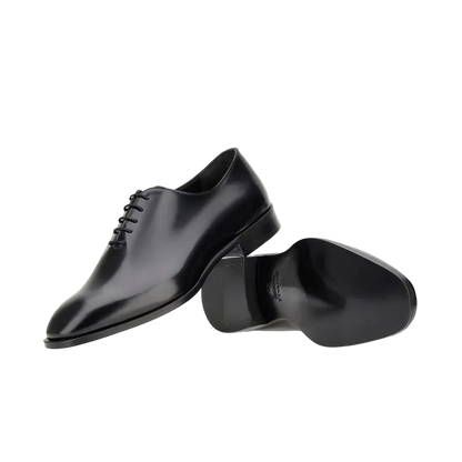 The Canali Black Calf Leather Wholecut Oxford Shoes are shown on a plain white background; one displays the smooth closed-lace upper, while the other reveals the polished seamless sole—ideal formal footwear. , available at Richard Gelding Mayfair