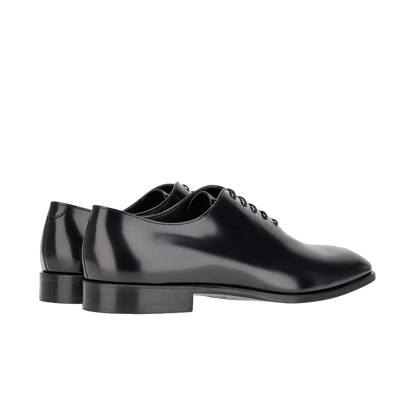 The Canali Black Calf Leather Wholecut Oxford Shoes feature shiny black leather, closed lacing, low black heels, and slightly rounded toes. Shown on a light grey background, side and rear view. Ideal as formal footwear. , available at Richard Gelding Mayfair