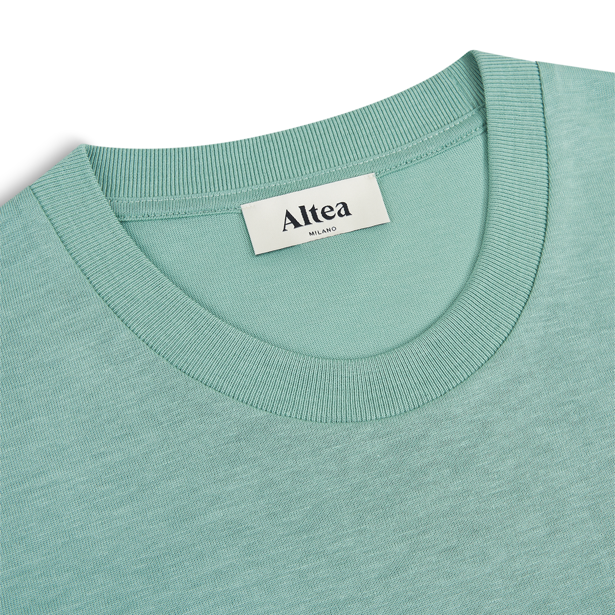 Close-up of a green Lyocell crew-neck T-shirt by Altea, with a ribbed collar and white brand label sewn inside the neckline. The shirt is laid flat on a white background. , available at Richard Gelding Mayfair
