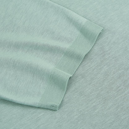 Close-up of Altea’s Green Lyocell T-shirt, featuring the ribbed cuff of a long sleeve on a flat surface. The soft, mint-green knit and fine ribbing highlight the T-shirt’s stretch and smooth texture. , available at Richard Gelding Mayfair