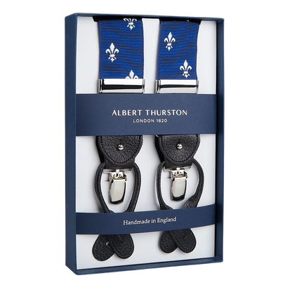 A box encases Albert Thurston's "Blue with White French Lily 40mm Braces," featuring black leather ends and silver clips. The label states "Albert Thurston London 1820" and "Handmade in England," epitomizing an elegant wardrobe essential.