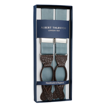 A pair of Albert Thurston Dove Grey James Bond Nylon 35mm braces with blue straps and brown leather detailing, presented in an elegant box labeled "Handmade in England".