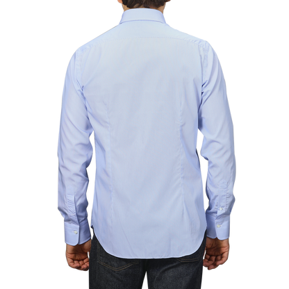 A person wearing an Alessandro Gherardi Blue Thin Striped Cotton Single Cuff Shirt and dark jeans, seen from the back against a plain gray background.