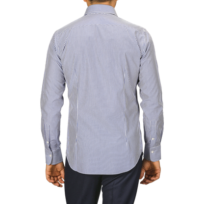 A person is standing with their back to the camera, wearing an Alessandro Gherardi Dark Blue Striped Cotton Single Cuff Shirt and paired with dark pants.