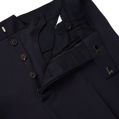 A pair of Alexander Kraft Monte Carlo Navy Blue Textured Worsted Wool Riviera Trousers with buttons on the side.