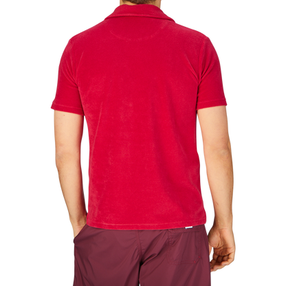 Rear view of a person wearing an Altea Coral Red Cotton Towelling Capri Collar Polo Shirt and maroon shorts against a grey background.