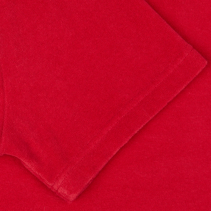 A coral red organic cotton towelling fabric or textile with a smooth texture laid out flat.