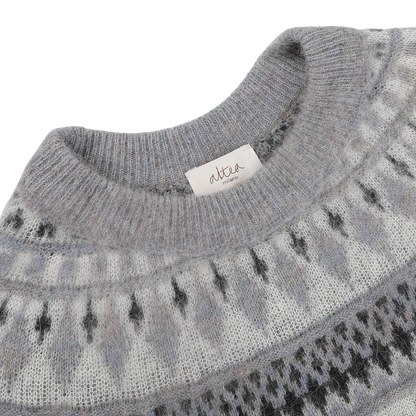Close-up of a grey melange Norwegian wool-alpaca blend crewneck with a geometric pattern and a tag reading "Altea Milano".