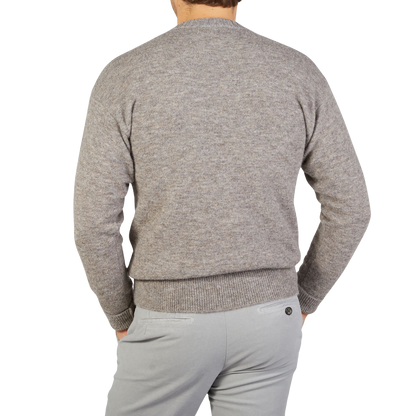 The back view of a man wearing an Altea Grey Melange Wool Alpaca Crewneck Sweater and gray pants.