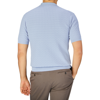 A man standing with his back to the camera, wearing a Altea Light Blue Cotton Capri Collar Polo shirt and beige trousers.