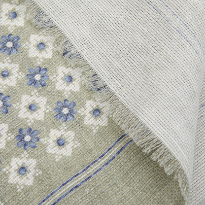 Close-up of an Amanda Christensen Olive Green Floral Printed Linen Cotton Scarf peeking under a solid gray fabric with frayed edges.