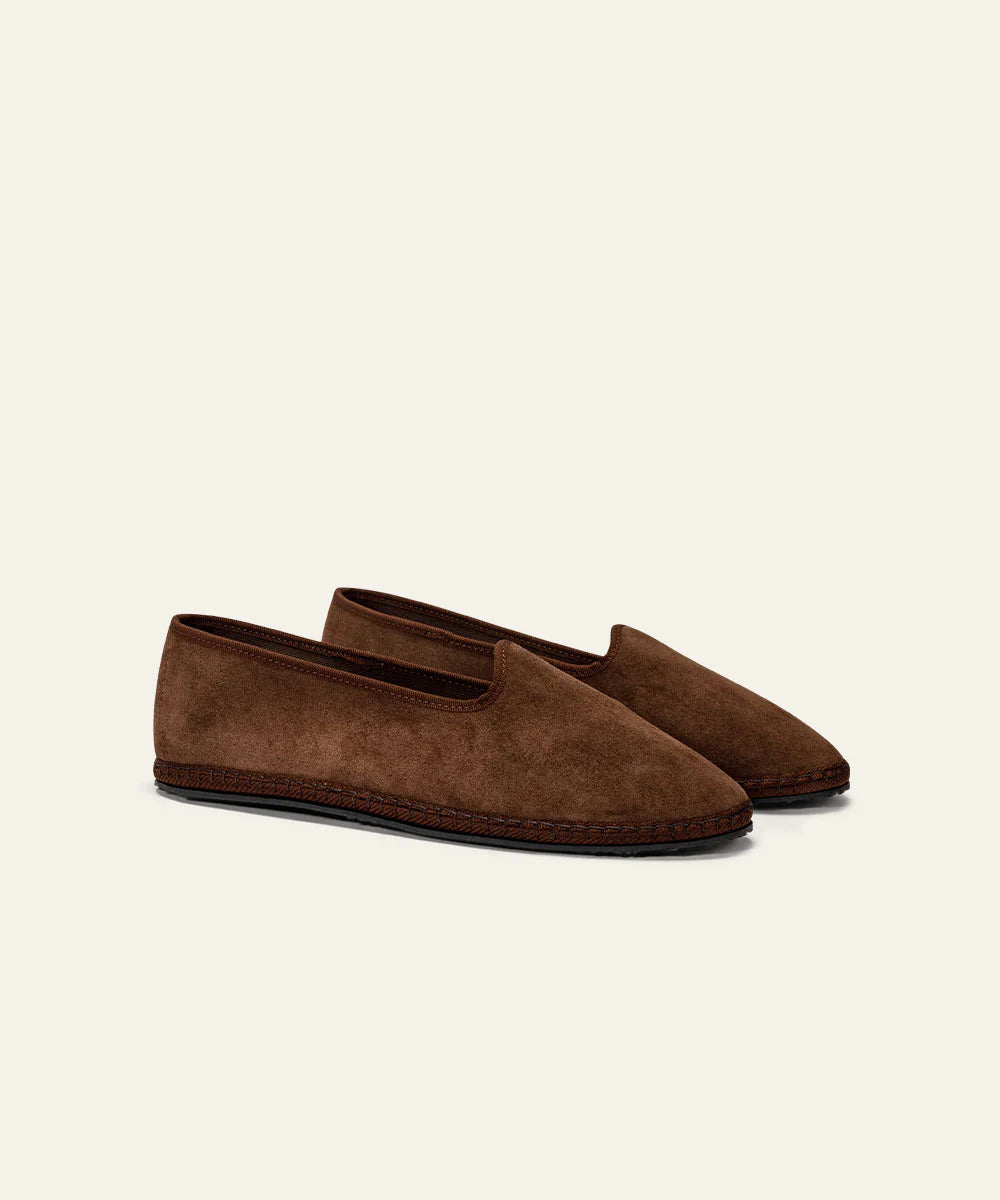 The Azaleri Dark Brown Suede Friulane Certosa shoes feature a minimalist, lace-free slip-on design with rounded toes and dark brown soles, shown side by side on an off-white background. , available at Richard Gelding Mayfair