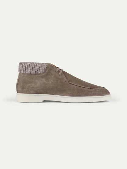 Introducing the Ash Grey Suede Desert Boots with Cashwool Trim by Aurélien—an ankle-high shoe crafted from taupe suede, featuring moccasin-style stitching, a ribbed knit collar, white sole, and laces. Inspired by Italian craftsmanship and reminiscent of classic Aurélien desert boots, these minimalist shoes are photographed from the side on a white background for a clean, casual look. , available at Richard Gelding Mayfair