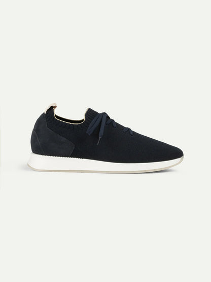 The Aurélien Navy Active Knit Wool Sneakers feature a navy knit wool upper, navy laces, and a white sole. This low-profile design offers casual luxury with a heel pull tab and no visible branding, shown on a plain white background. , available at Richard Gelding Mayfair