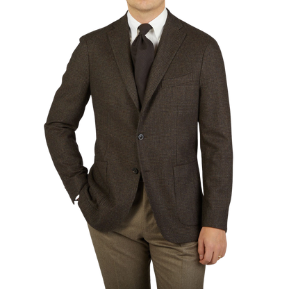 A man is posing in a Boglioli Brown Checked Lambswool K Jacket, showcasing the unstructured craftsmanship of his brown suit and tan pants, proudly made in Italy.
